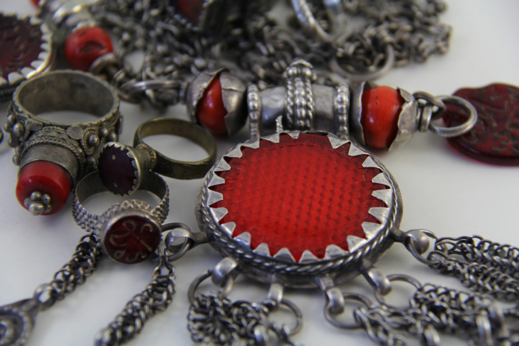 An Omani pendant set with a reflector. Depicted with it are Yemeni rings with red glass insets