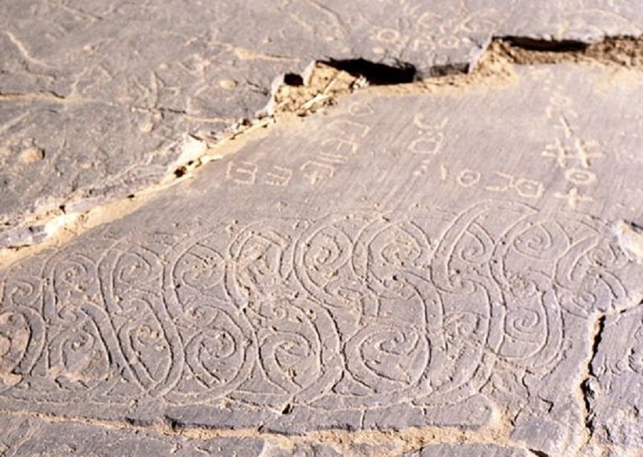 Rock art in the Algerian Sahara with an example of the Tifinagh script used by the Tamazight language family. Picture via Wiki Commons