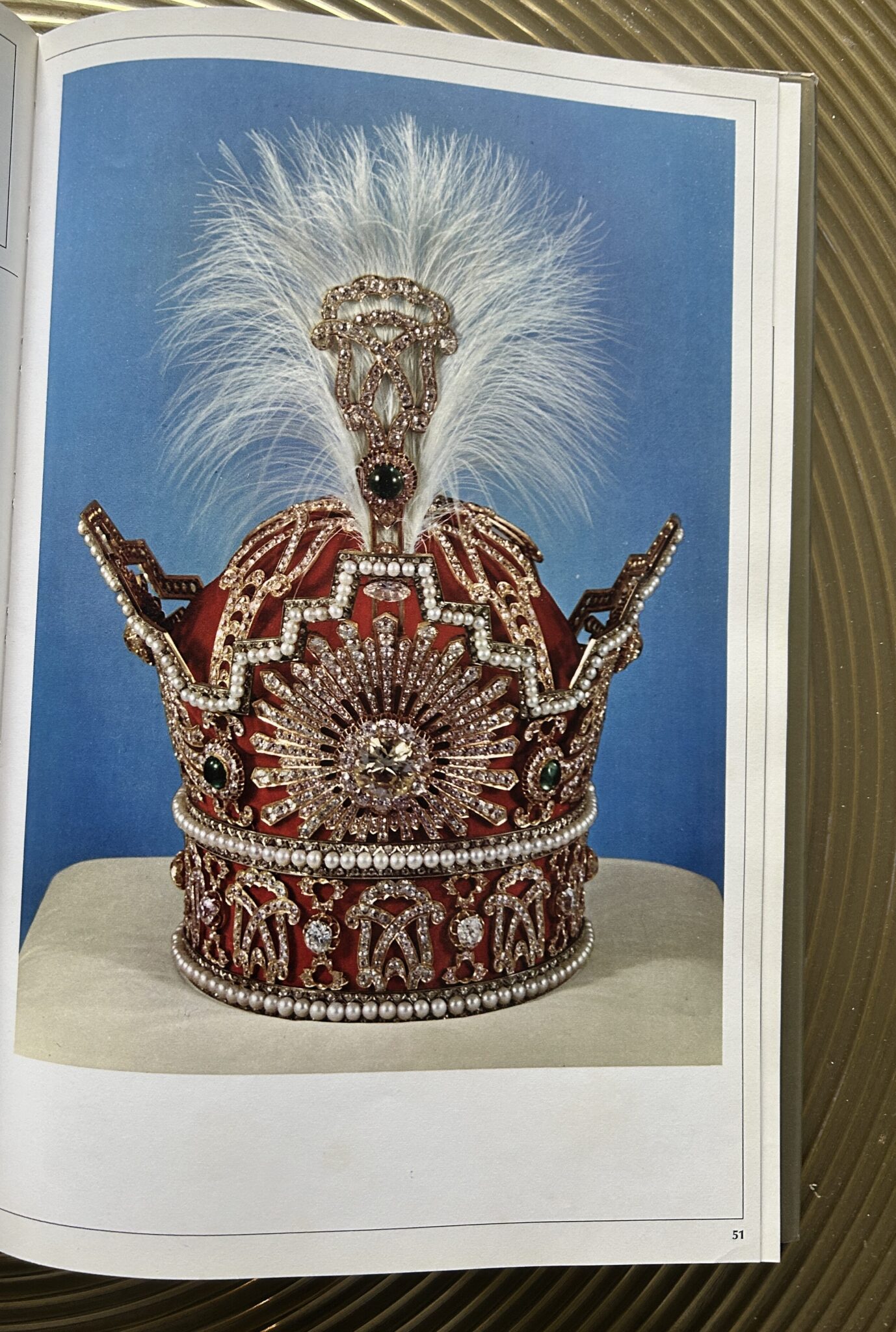 Image of the Pahlavi Crown, a gold, silver and red velvet crown with a large plume